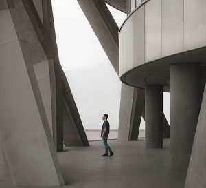 Man walking through some columns in an industrial building