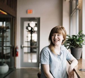 Photo of a smiling woman leaning on a wooden ledge or shelf