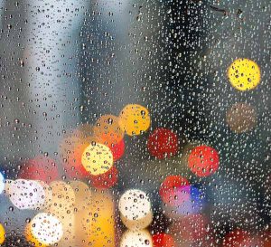 Rain on window with coloured lights in the background