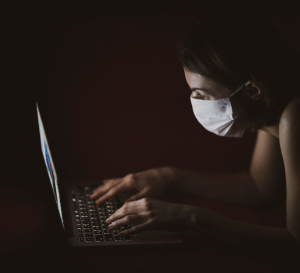 Woman wearing mask and typing at laptop