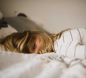 woman lying down on bed with hair covering face