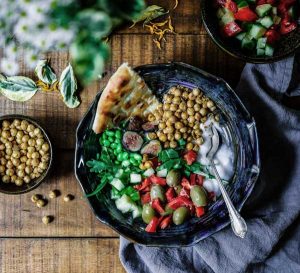 A plate of healthy food including chick peas, peppers and greens